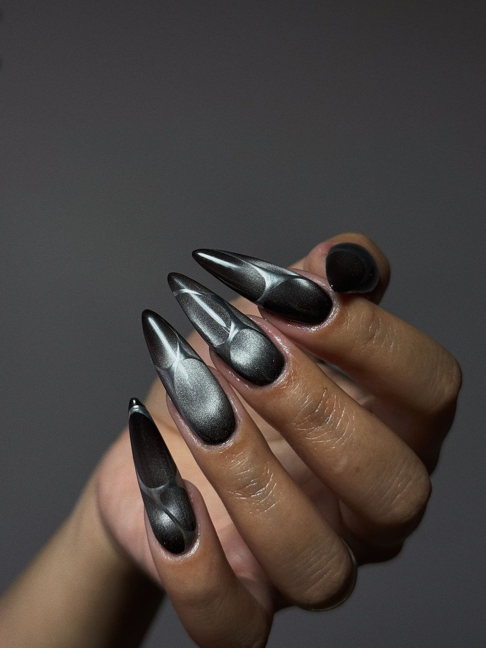 Black silver cat eye long stiletto nails on dark skin, black magnetic stilettos with a silver band