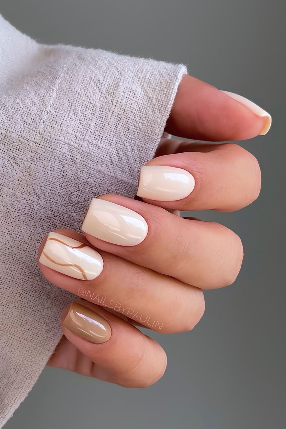 Cream short nails with gold swirl lines, cream set with fine metallic swirls