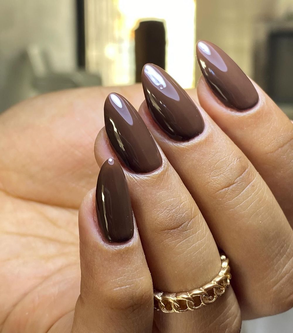 Glossy cocoa almond nails with a gold ring, warm brown set with gold jewelry