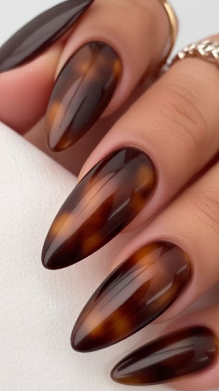 Glossy tortoiseshell stiletto nails, amber marble at stiletto length and shine