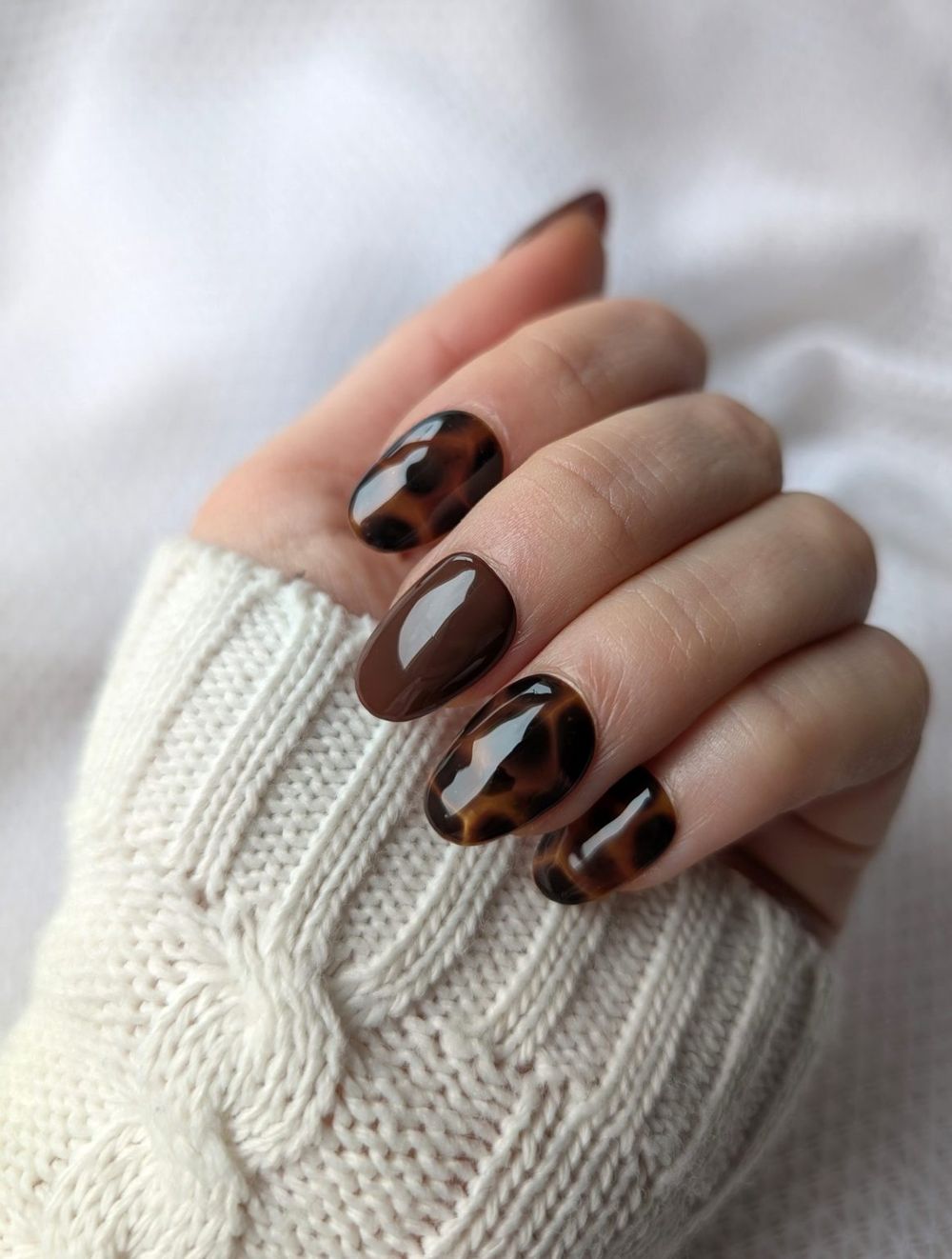 Tortoiseshell short nails in a white knit, amber marble short set with a sweater sleeve