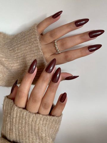 Burgundy almond nails in a beige knit, both hands in a deep wine gel set