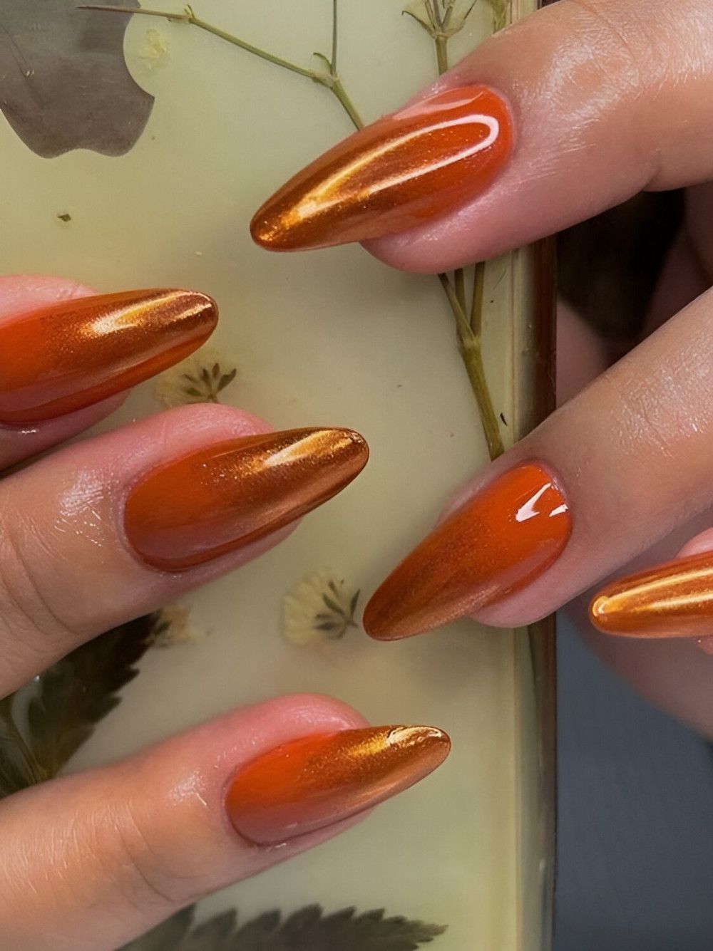 Copper chrome almond nails with a metallic burnt orange mirror finish