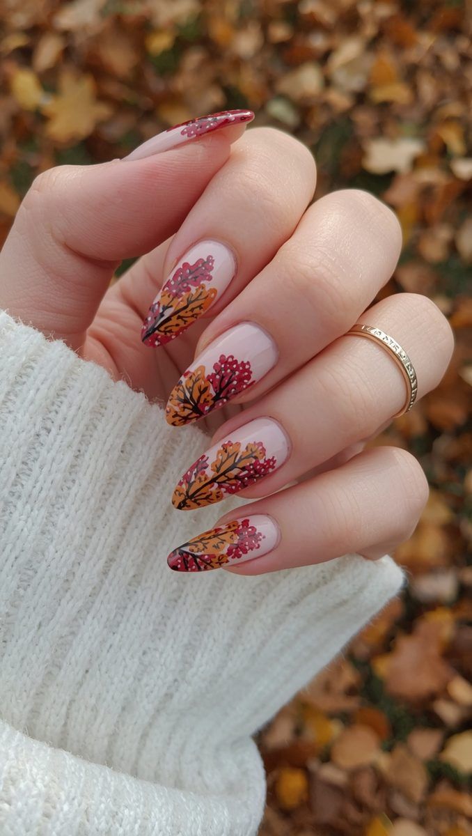 Almond nails with floral fall art in red and gold over a clear base, knit and autumn leaves