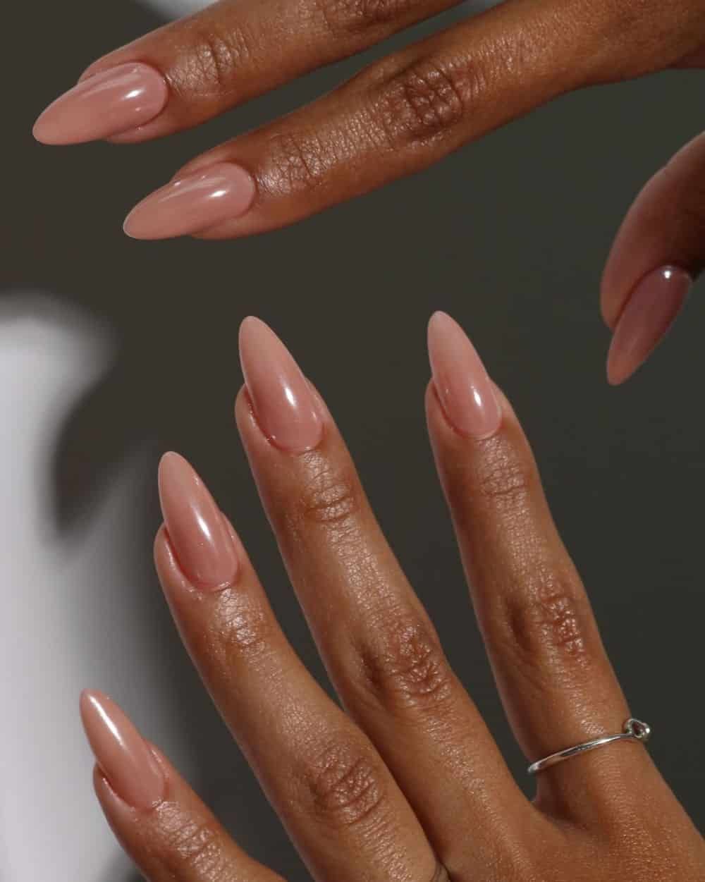 Glossy nude almond nails on dark skin, clean sheer brown nude gel set