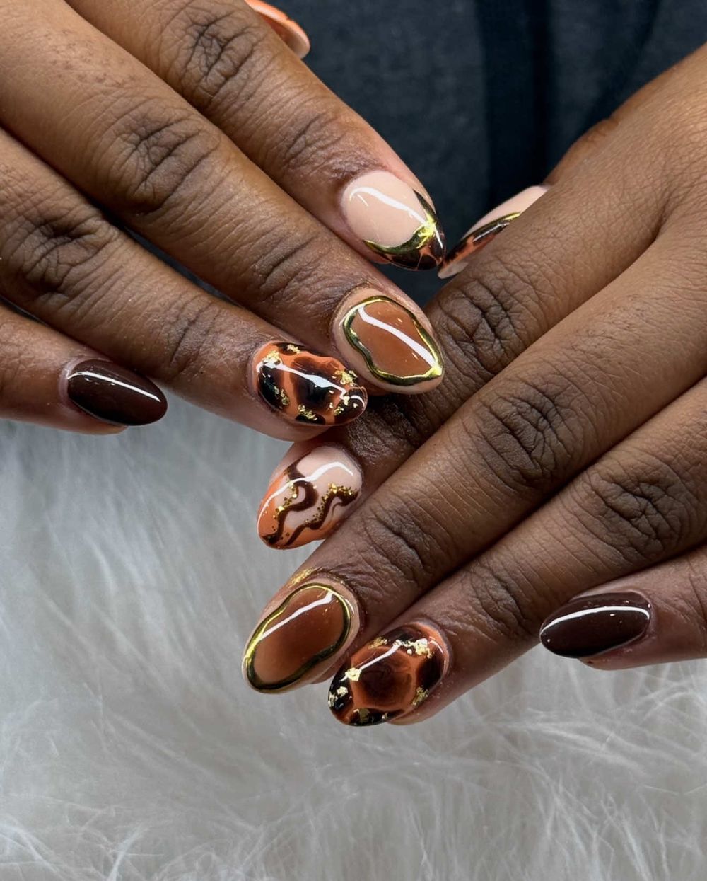 Tortoise art almond nails on dark skin with gold outlined amber and black marbling