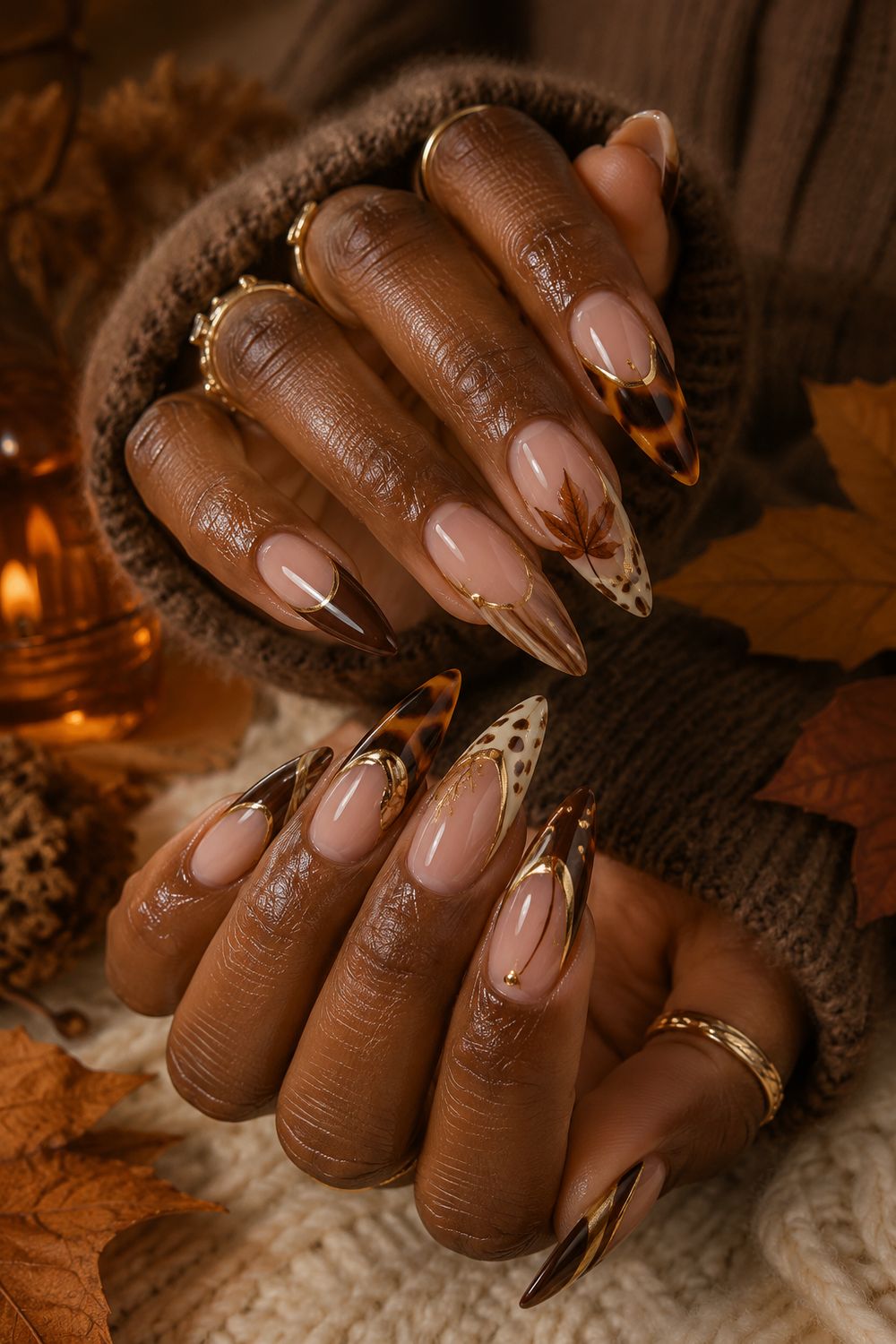 Tortoise French almond nails on dark skin with gold leaf art, autumn leaves around the hands