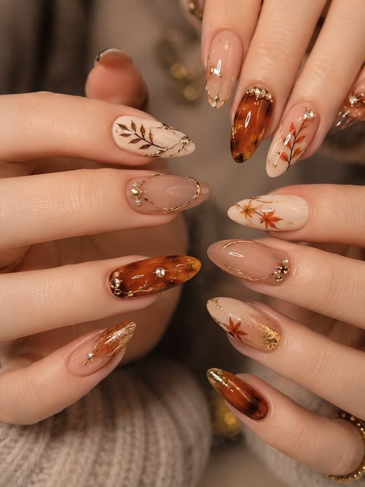 Amber tortoiseshell nails with gold leaf art on both hands, glossy caramel and bronze set