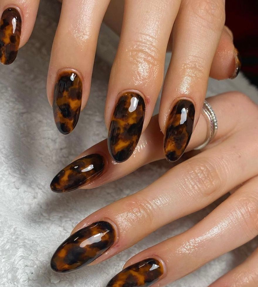 Classic tortoiseshell almond nails with amber, black and caramel marbling on a glossy long set