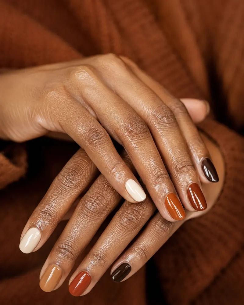 Fall multicolor nails on brown skin, cream rust and chocolate shades alternating across both hands