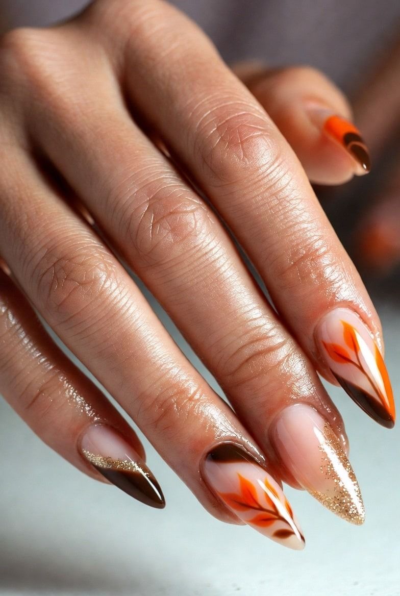 Orange flame French stiletto nails with burnt orange flame tips over a nude base and glitter accents