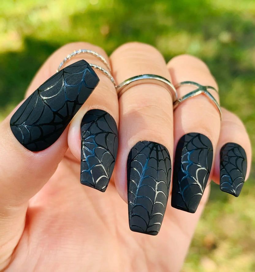 Glossy black coffin nails with subtle tonal spiderweb art, photographed outdoors