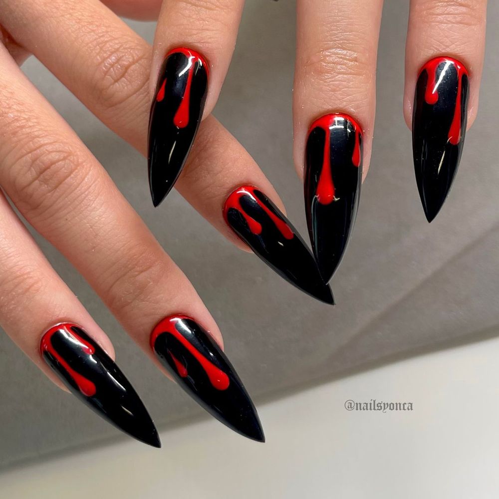Glossy black stiletto nails with red blood drip art running from the cuticle