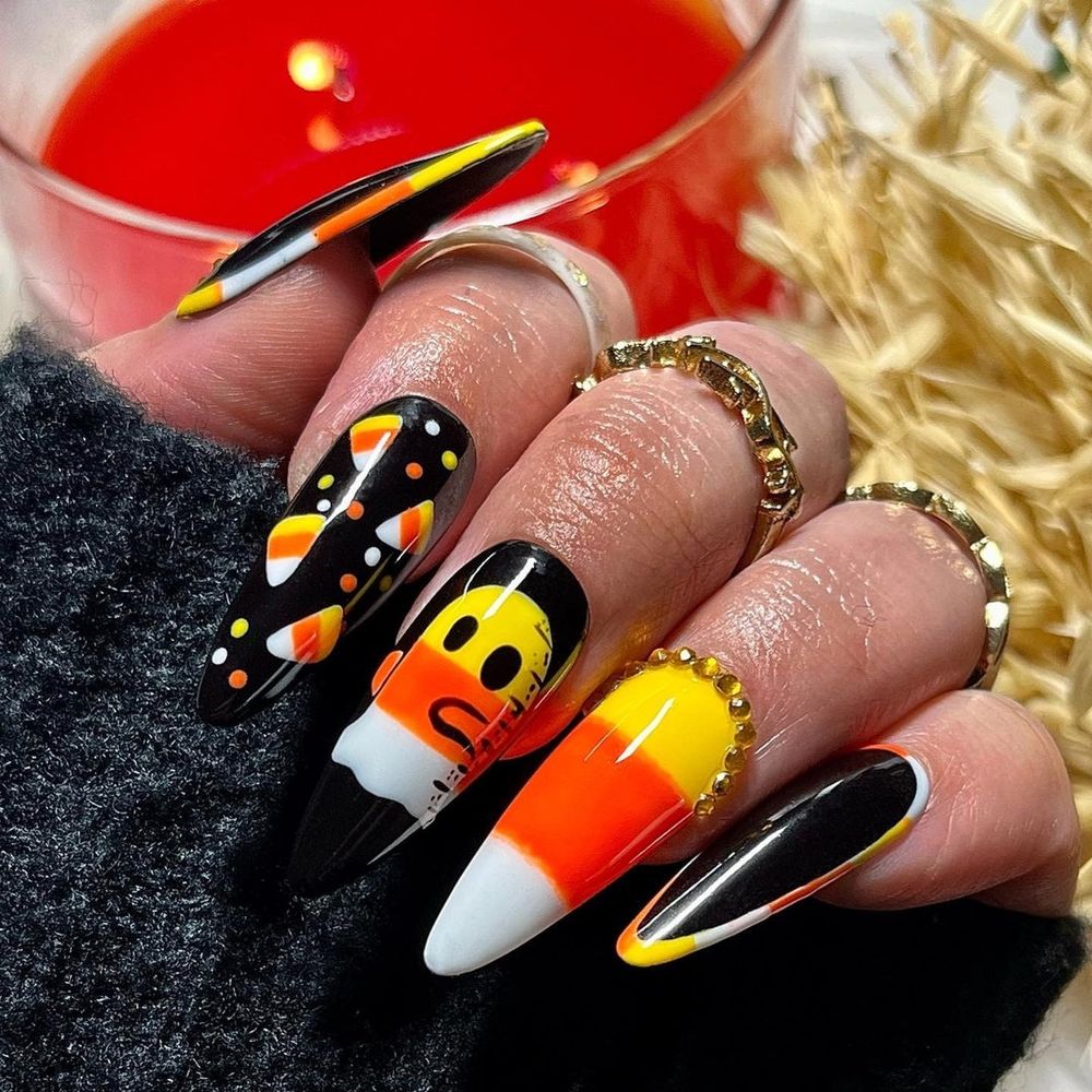 Candy corn stiletto nails in orange, yellow and white with ghost and candy corn art accents
