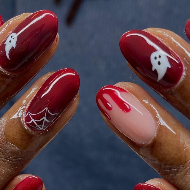 Deep red oval nails on dark skin with a white ghost, web art and blood drip accent