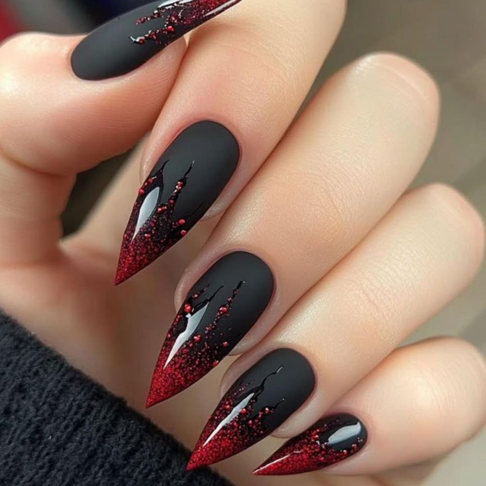 Matte black stiletto nails with red glitter claw slashes and glossy red glitter tips