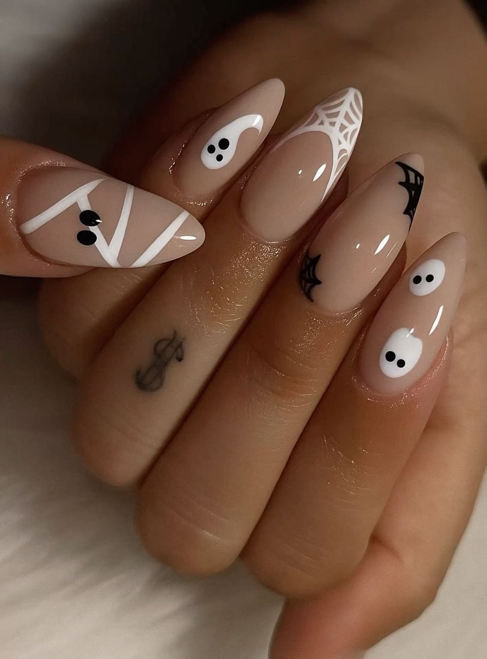 Nude almond nails on dark skin with white ghost art and a wrapped mummy accent nail