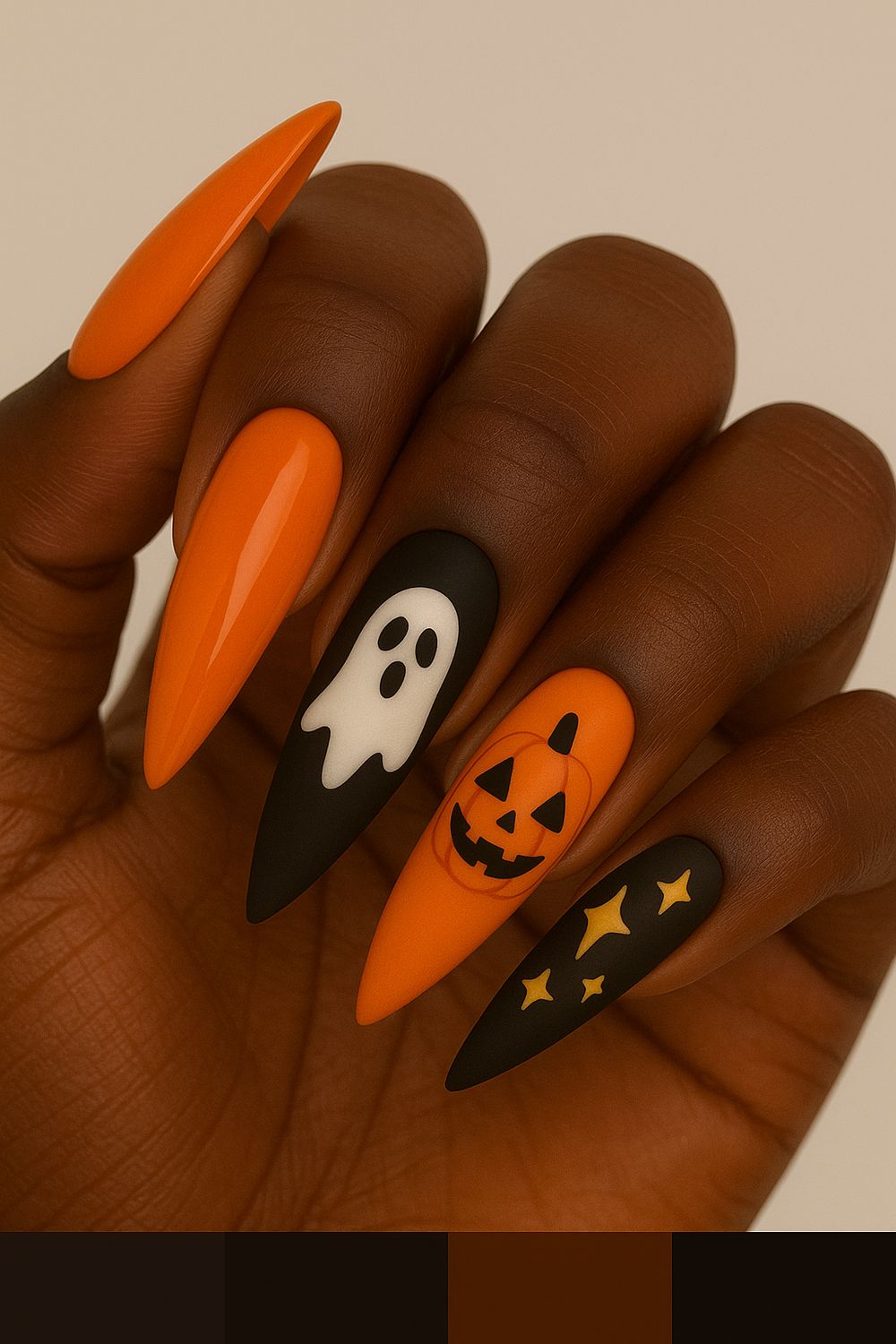 Orange and black stiletto nails on dark skin with a white ghost, jack-o-lantern and star accents