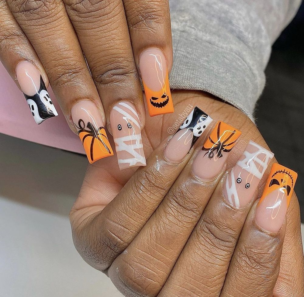 Orange and white short square nails on dark skin with mummy wrap, pumpkin and spider art mix