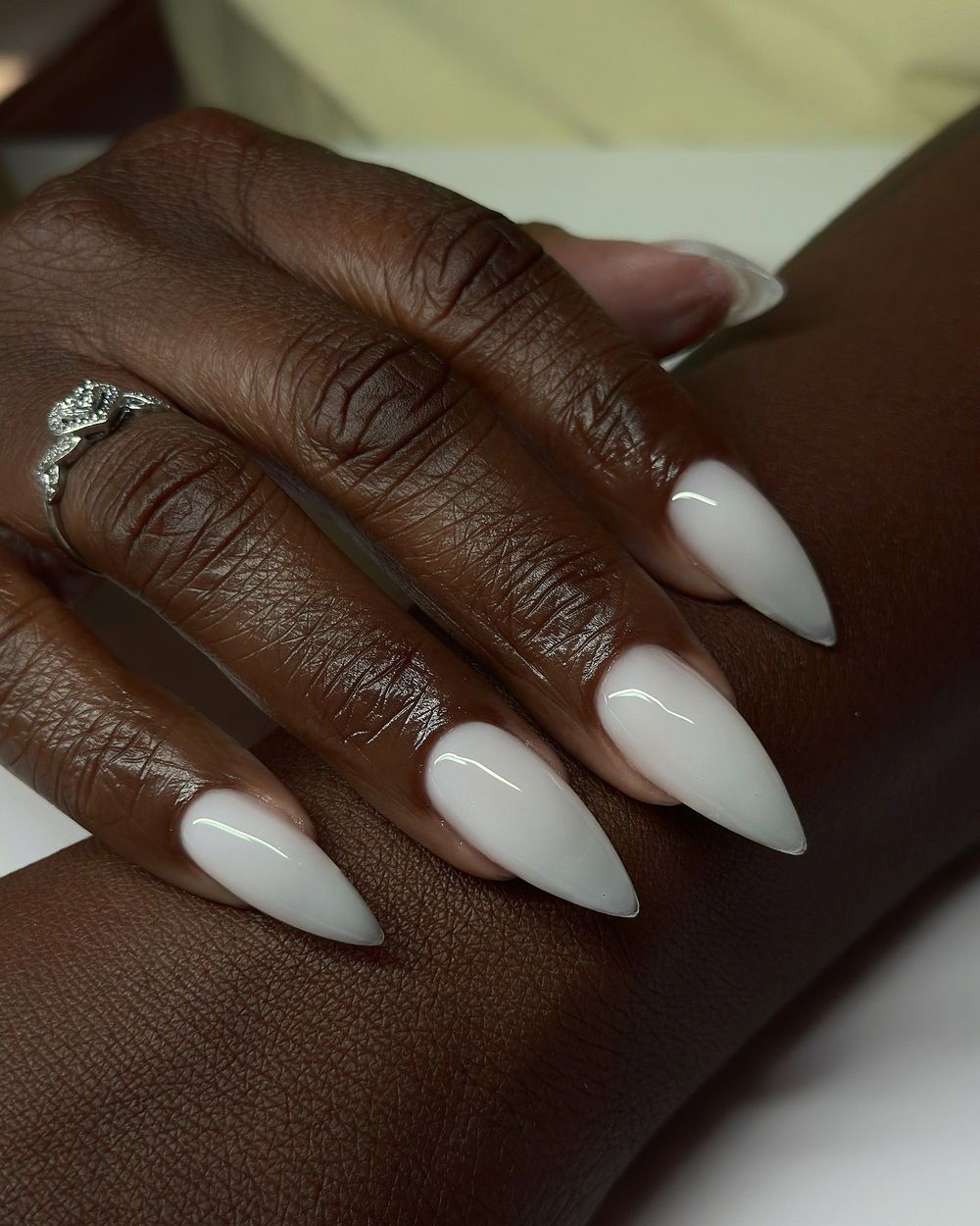 Glossy white long almond nails on dark skin, bright white at full length