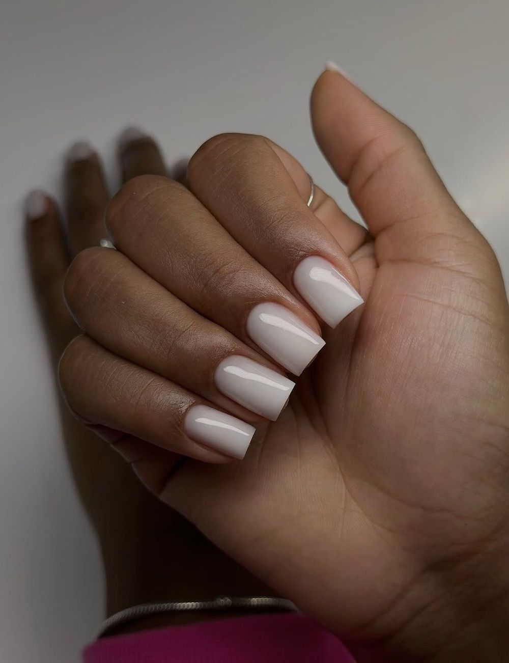 Milky white oval nails in a fist on brown skin, white ovals on warm skin