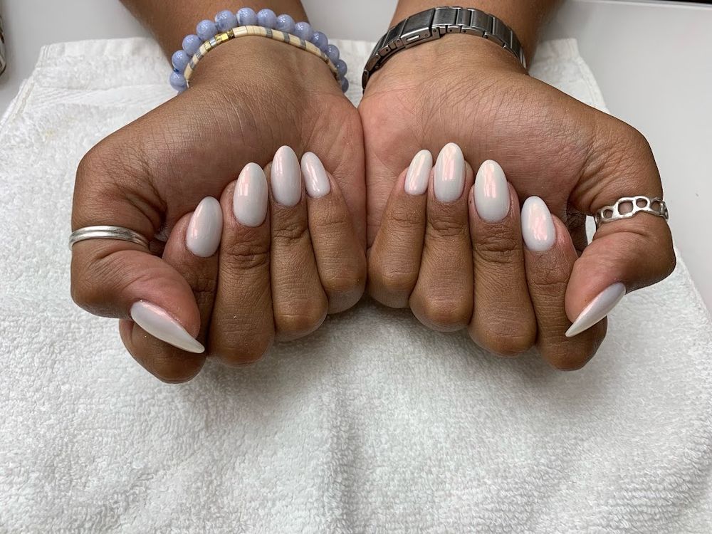 Milky white oval nails on dark skin in two fists, white ovals shown from above