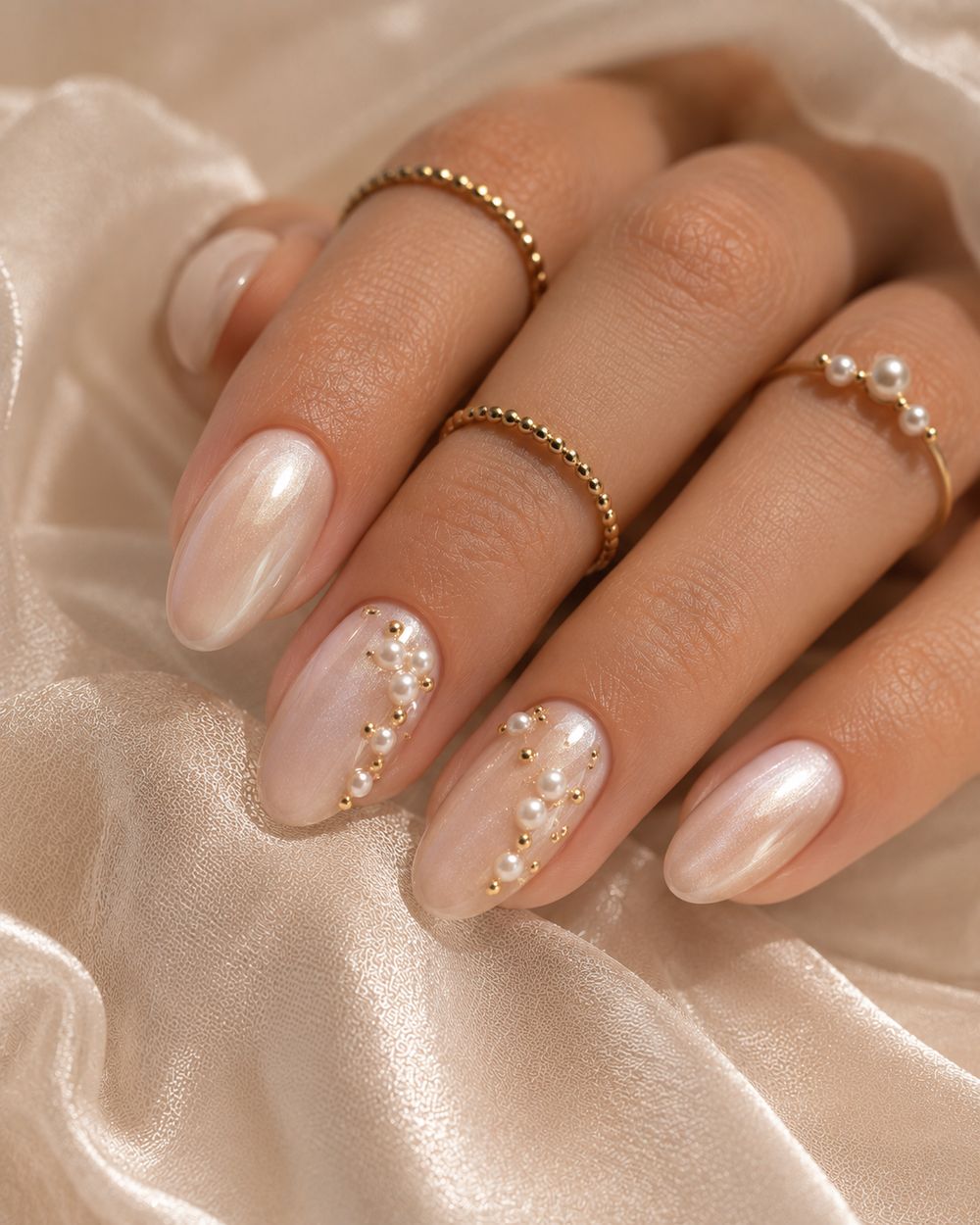 Pearl chrome almond nails with gold dot accents, pearl glow with tiny gold studs