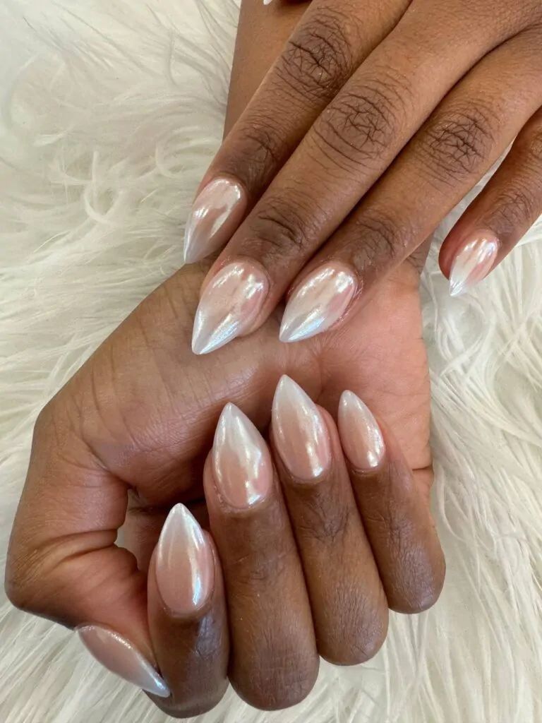 White chrome almond nails on dark skin with fur, white glow against a fur cuff