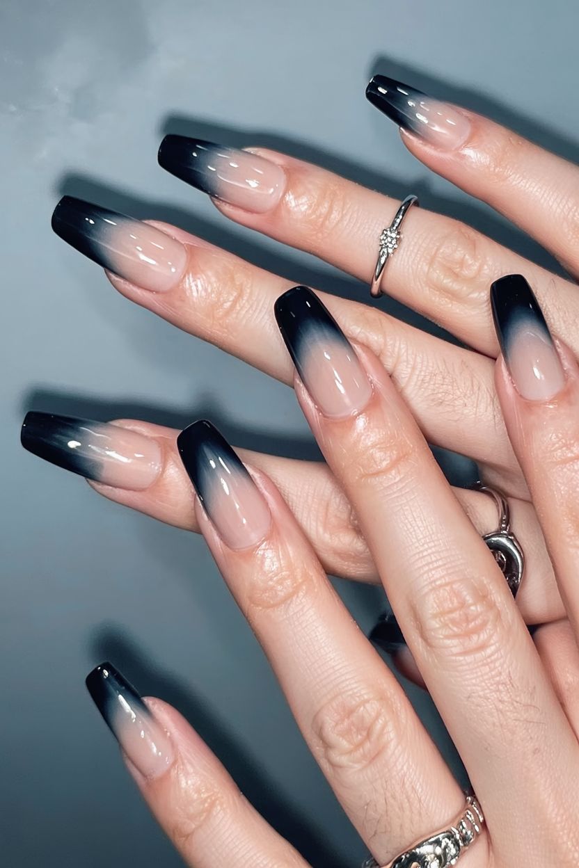 Black ombre French stiletto nails, black tips fading into a nude base