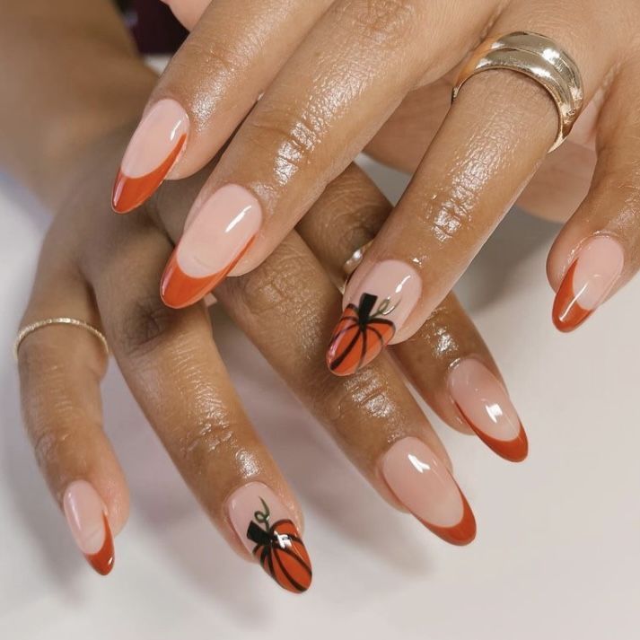 Burnt orange French almond nails with pumpkin art on brown skin, orange tips with tiny pumpkins