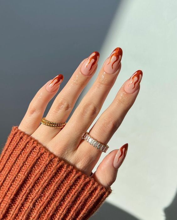Rust flame French stiletto nails in an orange knit, flame shaped rust tips at length