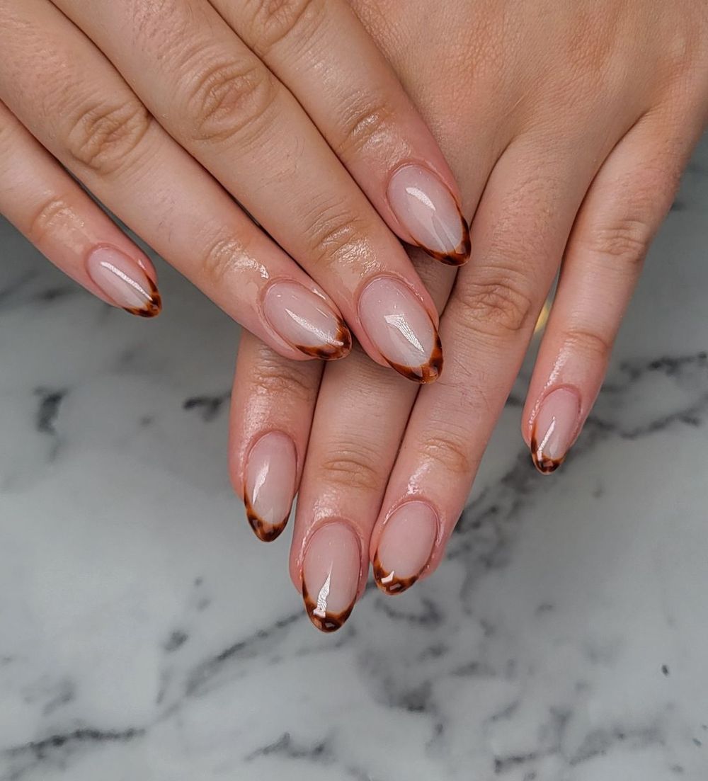 Tortoiseshell French almond nails on marble, nude base with amber tortoise tips