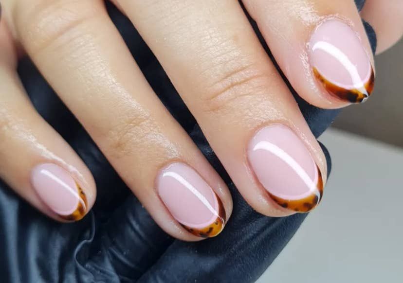 Tortoiseshell gold French short nails in a salon, tortoise and gold tips at short length