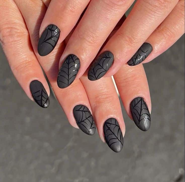 Matte black spiderweb nails, tonal black webs painted over a matte black base on almond nails