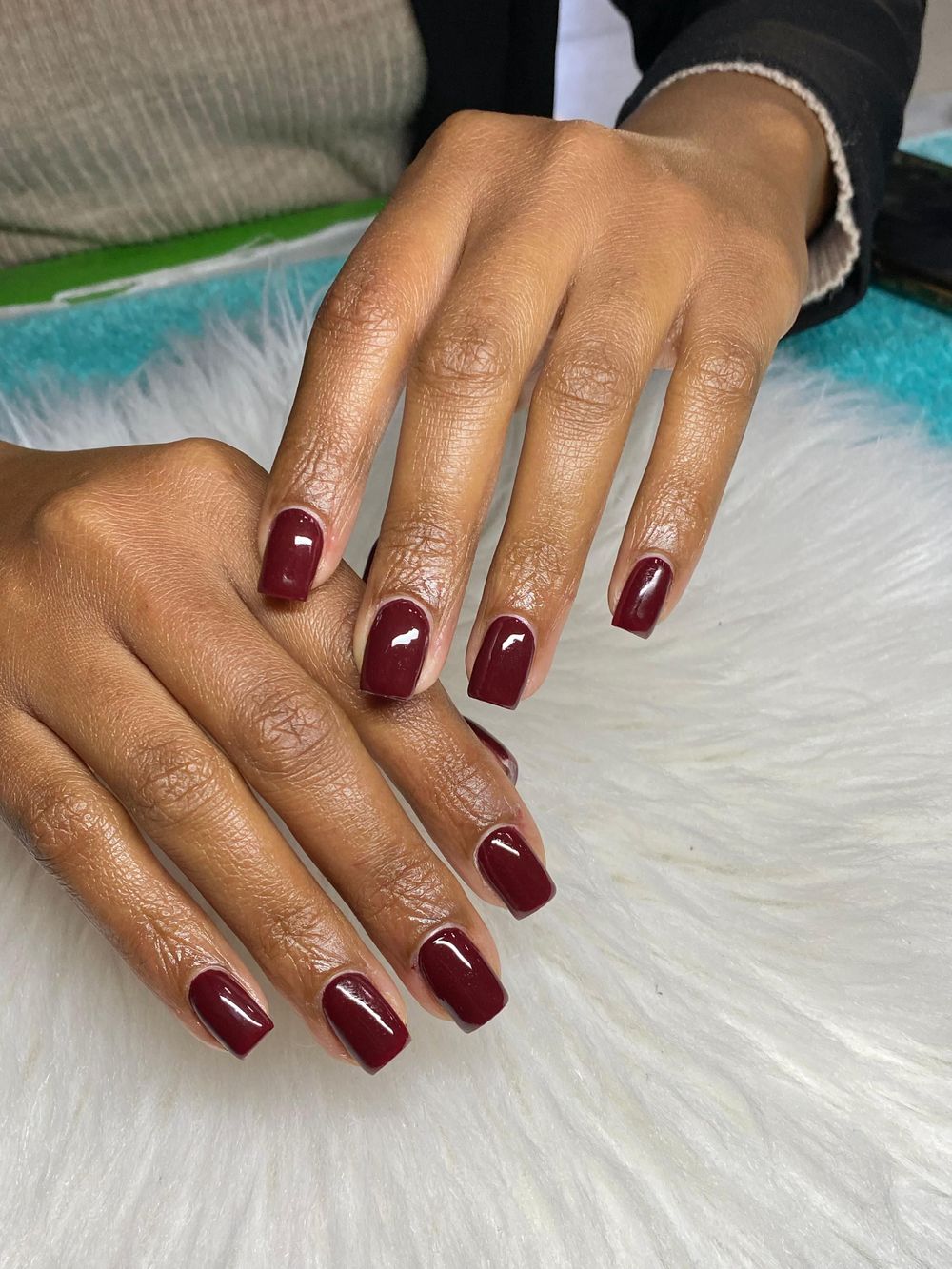 Burgundy short nails on dark skin with a salon finish, deep red glossy short set