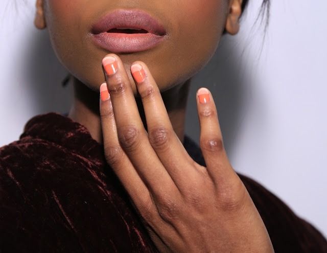 Coral orange French short nails on dark skin, bright coral tips over a nude base