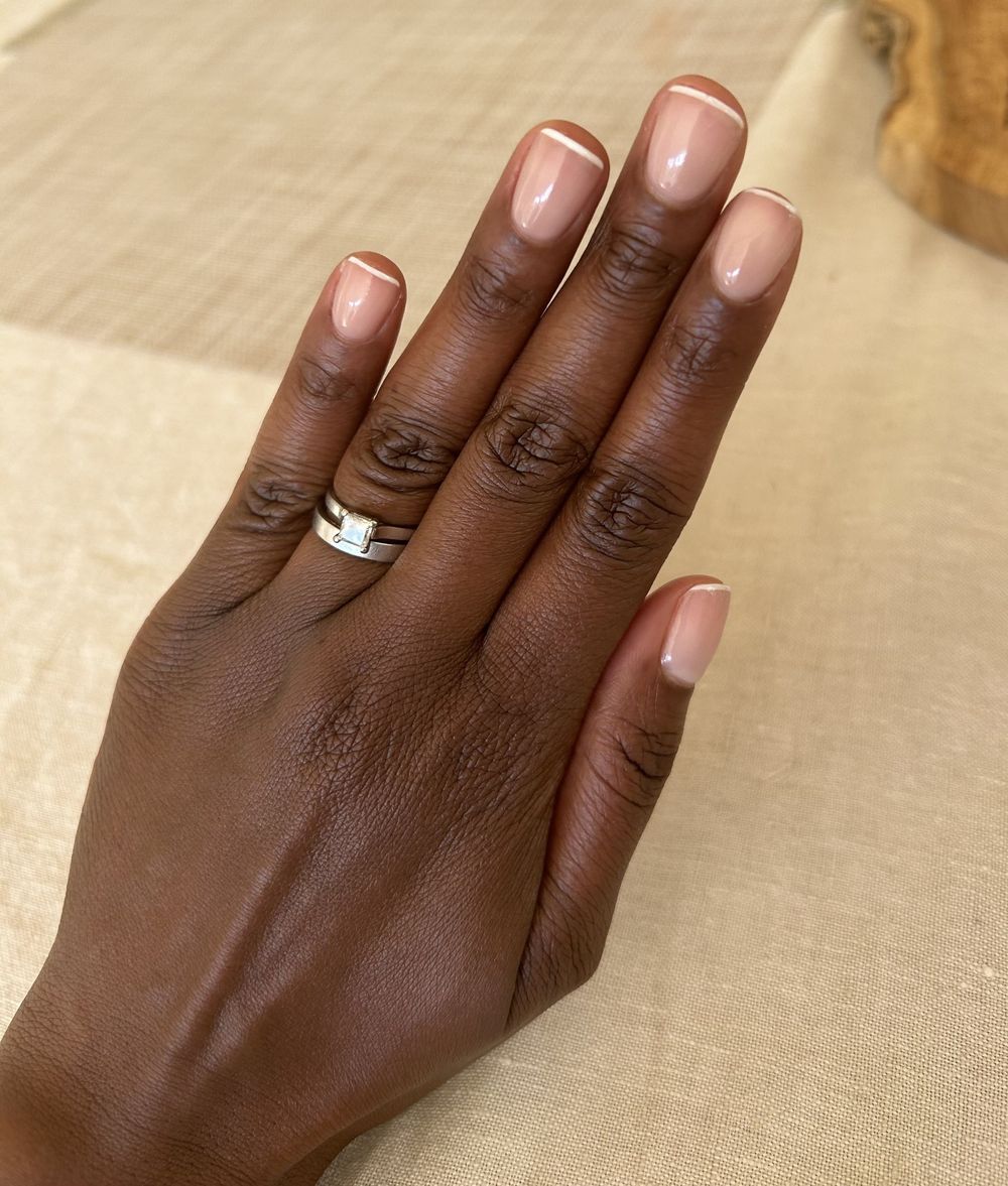 Milky French short nails on dark skin, milky white tips over a sheer base