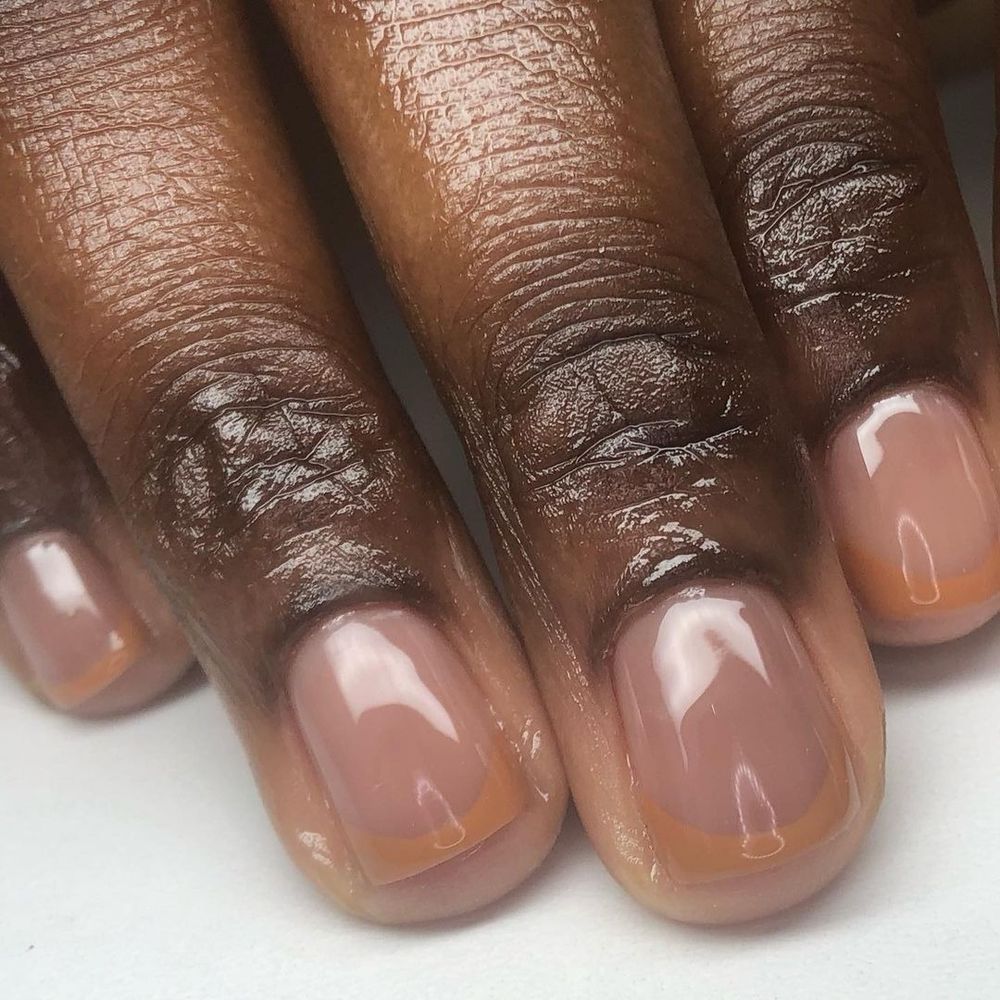 Nude French short nails on dark skin, sheer nude base with soft white tips