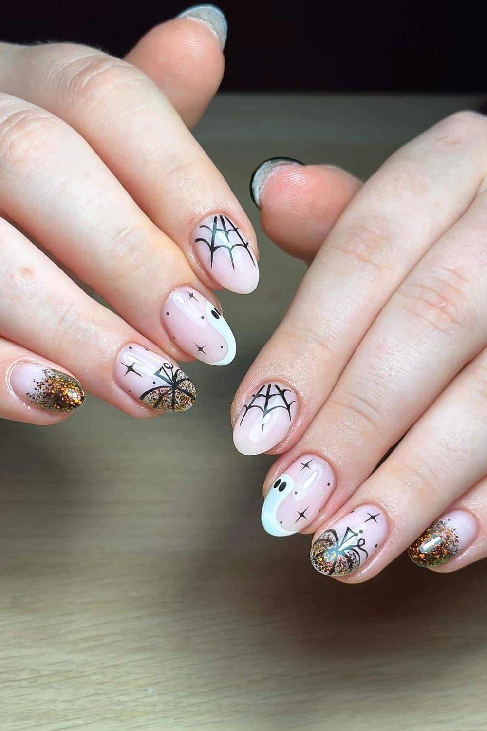 Spiderweb art short oval nails, pale base with black spiderweb and spider details