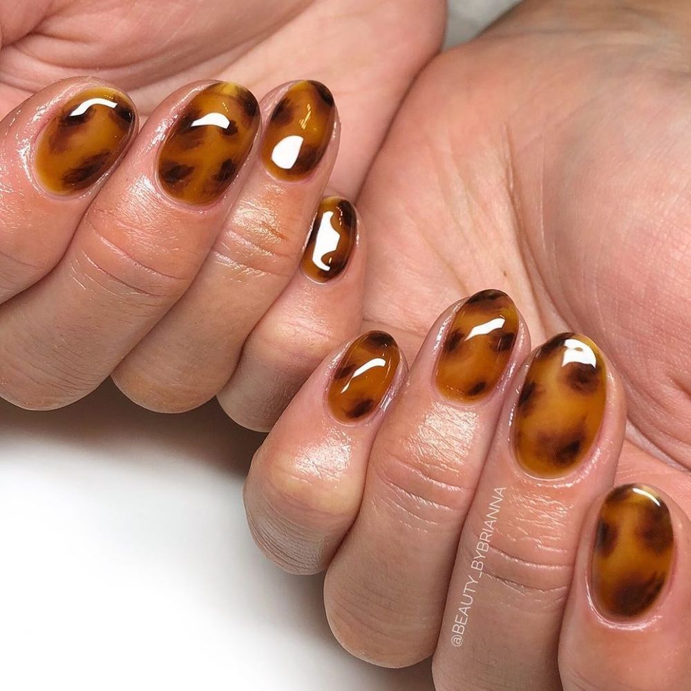 Amber tortoiseshell oval nails held in hand, bright amber marble oval set