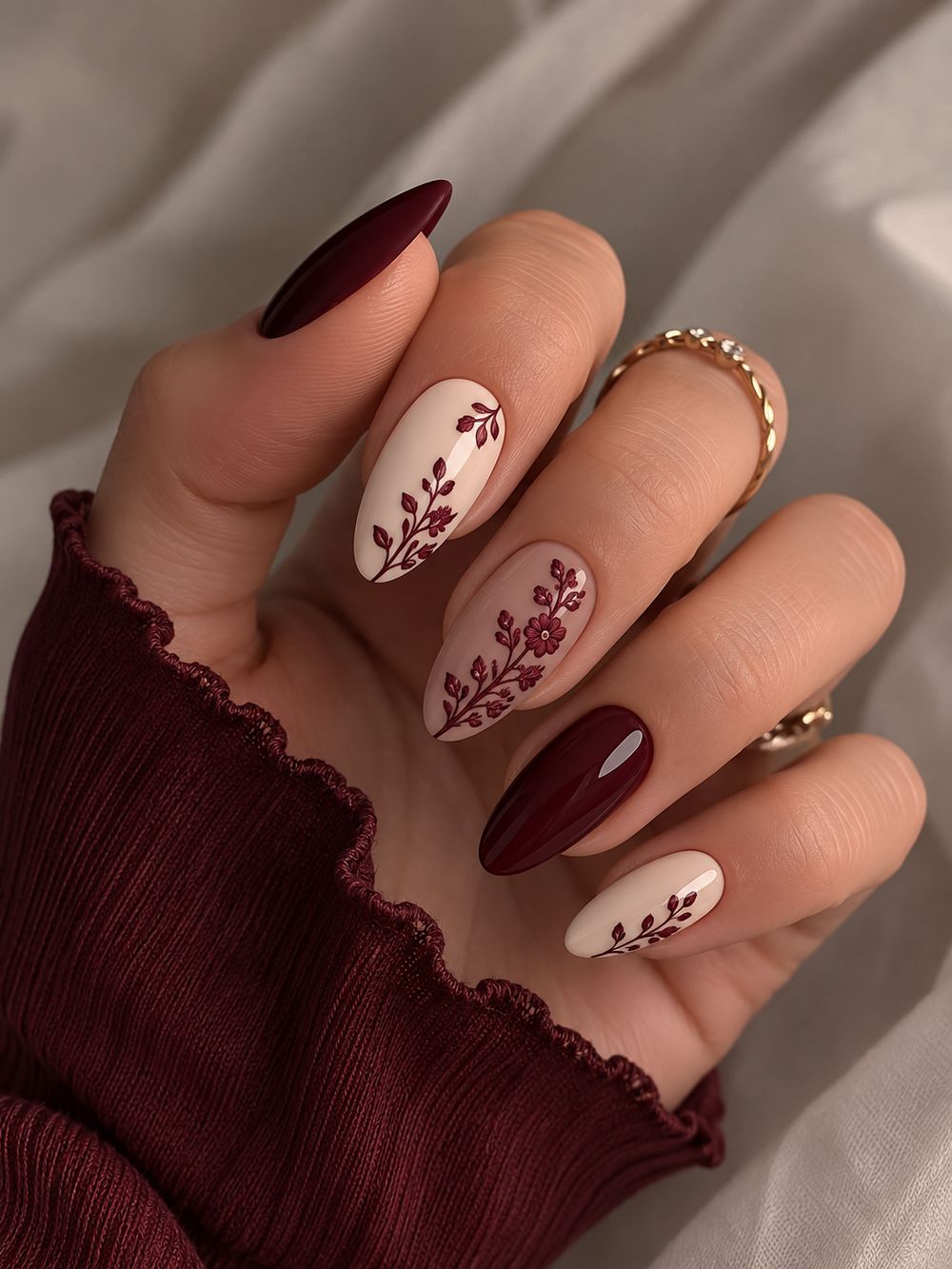 Burgundy almond nails with cream leaf art, deep red with hand painted cream leaves