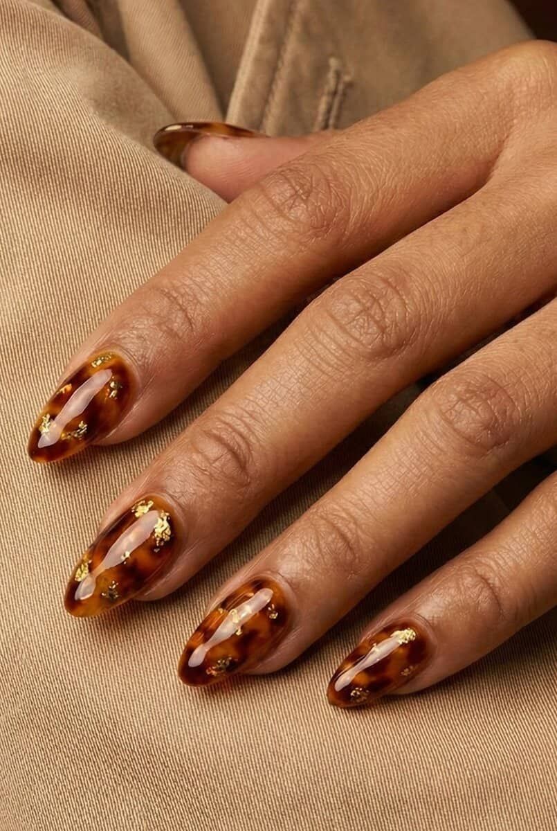 Classic tortoiseshell almond nails on brown skin, traditional amber marble almond set