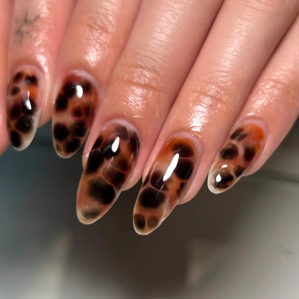 Glossy tortoiseshell almond nails, classic amber marble with a glass finish