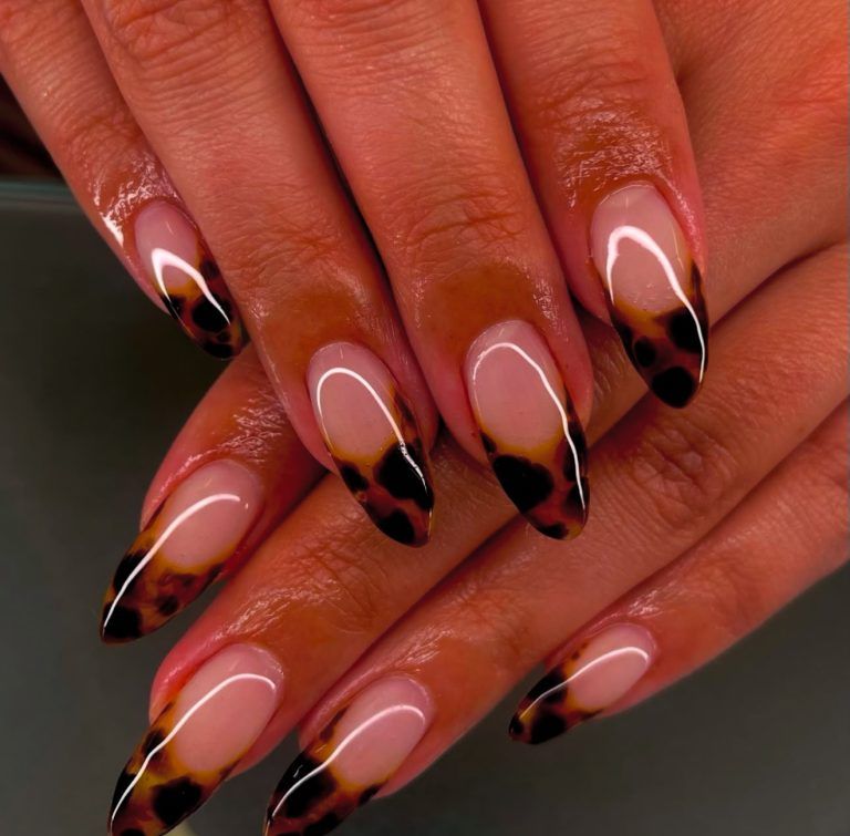 Tortoiseshell French almond nails in warm light, nude base with glowing amber tips